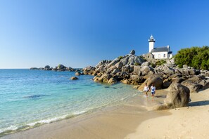 A lighthouse on a rocky shore with clear blue water.