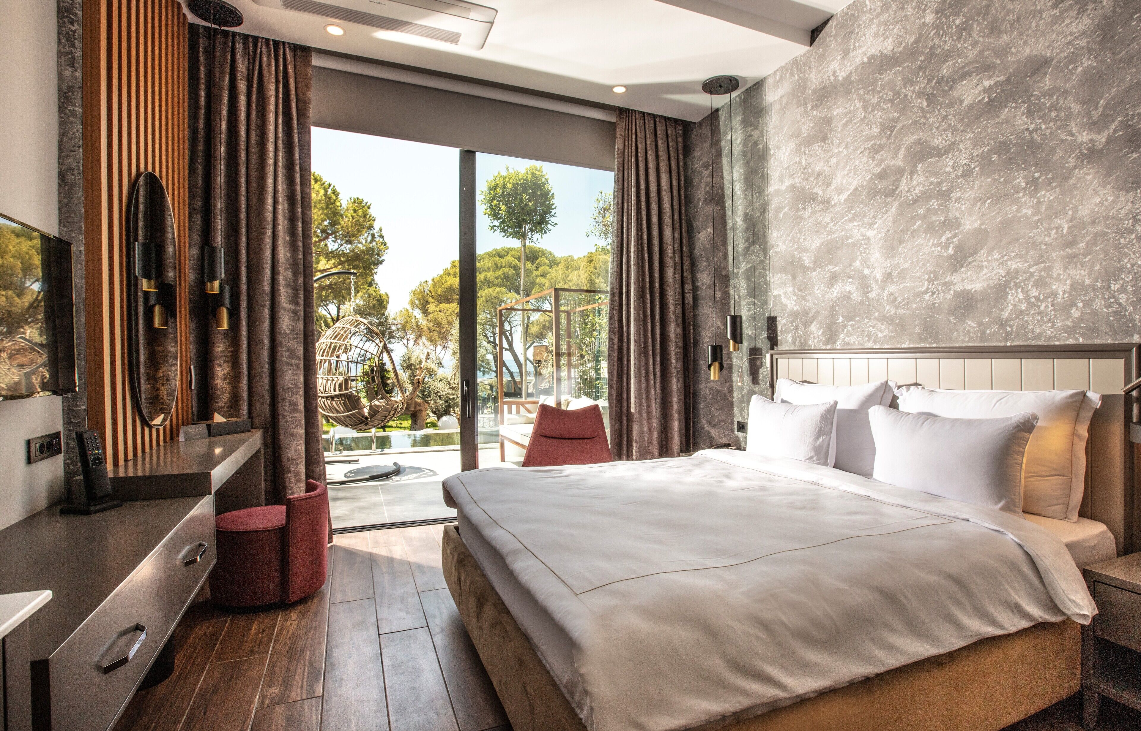Una habitación de hotel moderna con una cama grande, televisión, escritorio y vistas al exterior.