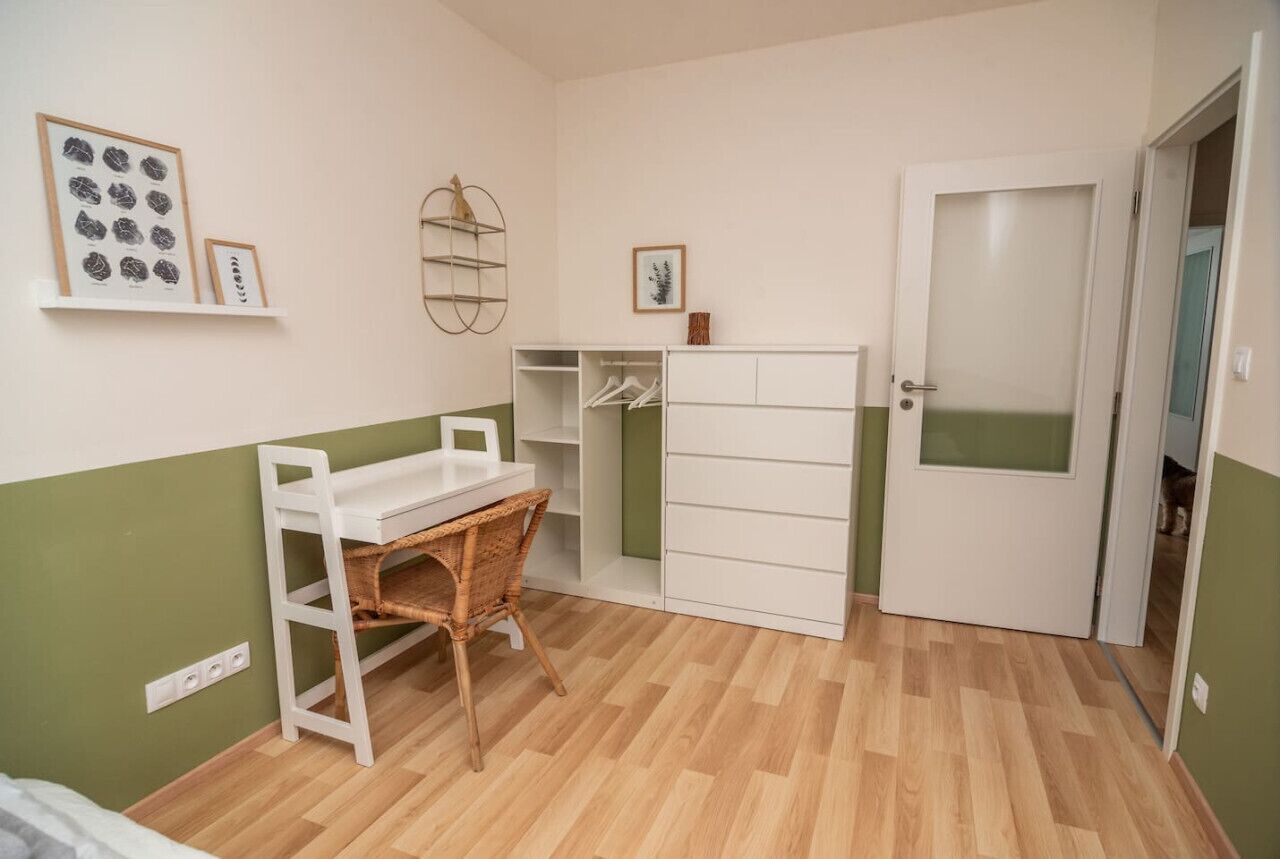 Une chambre à coucher avec un lit, un bureau, une armoire et une porte.