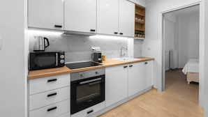 Eine moderne Küche mit weißen Schränken, einem schwarzen Backofen, einer Mikrowelle und einer Holz Arbeitsplatte.