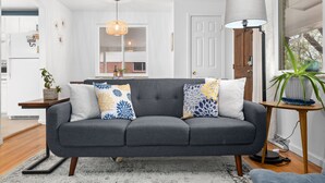 A modern living room with a grey sofa, a side table with a plant, and a floor lamp.