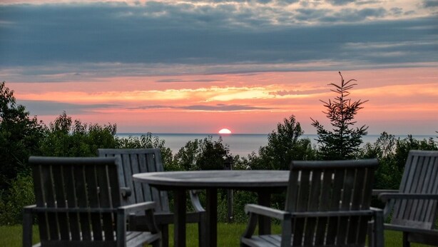 Sonnenuntergangblick von einer Terrasse mit einem runden Tisch und vier Stühlen.