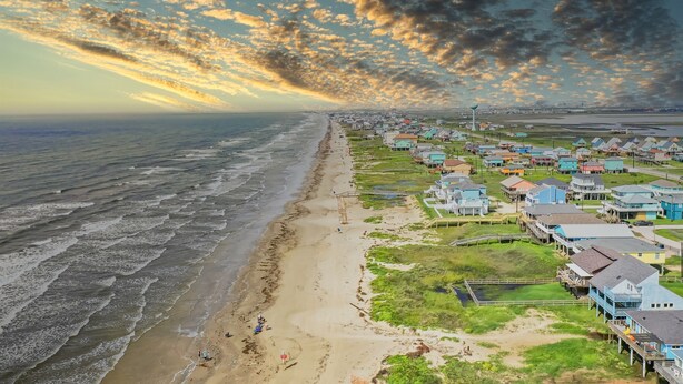 Une ville côtière avec des maisons donnant sur la plage, une plage de sable et une vue sur l’océan.