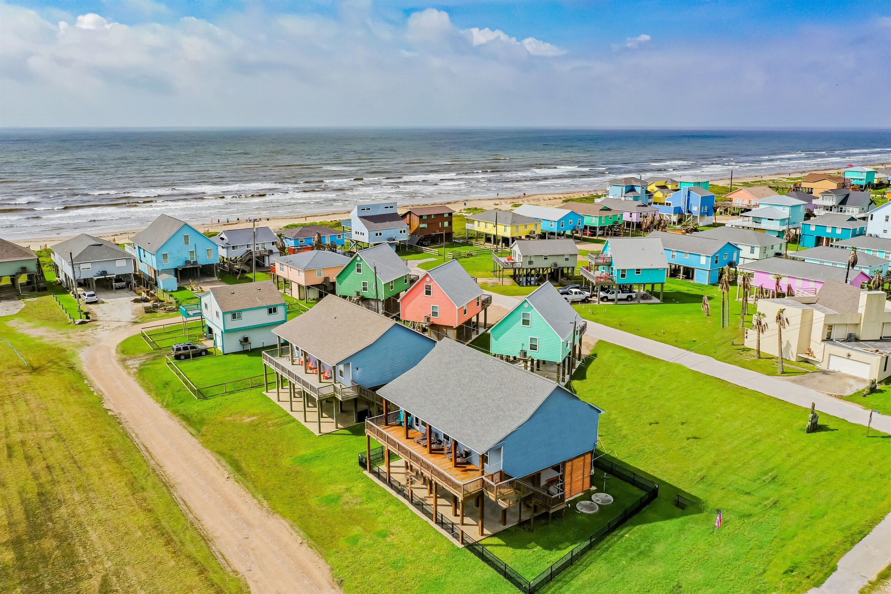 A coastal residential area with colorful houses, a beach, and a view of the ocean.