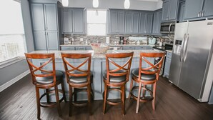 Une cuisine moderne avec des meubles gris, des appareils en acier inoxydable et un îlot central doté de tabourets de bar.