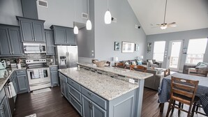 Une cuisine moderne dotée de plans de travail en granit, d’un grand îlot central et d’appareils électroménagers intégrés.