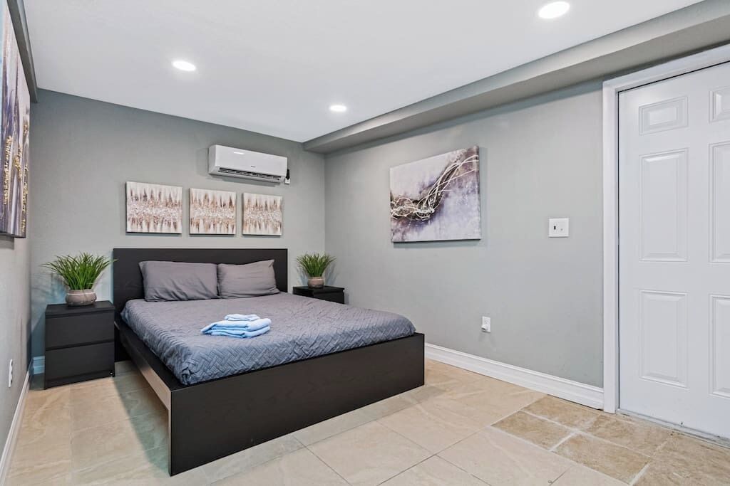 Une chambre à coucher moderne avec un lit, des tables de chevet et des œuvres d’art accrochées aux murs.