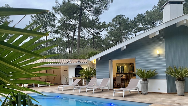 A poolside area with lounge chairs, a barbecue, and a dining area.