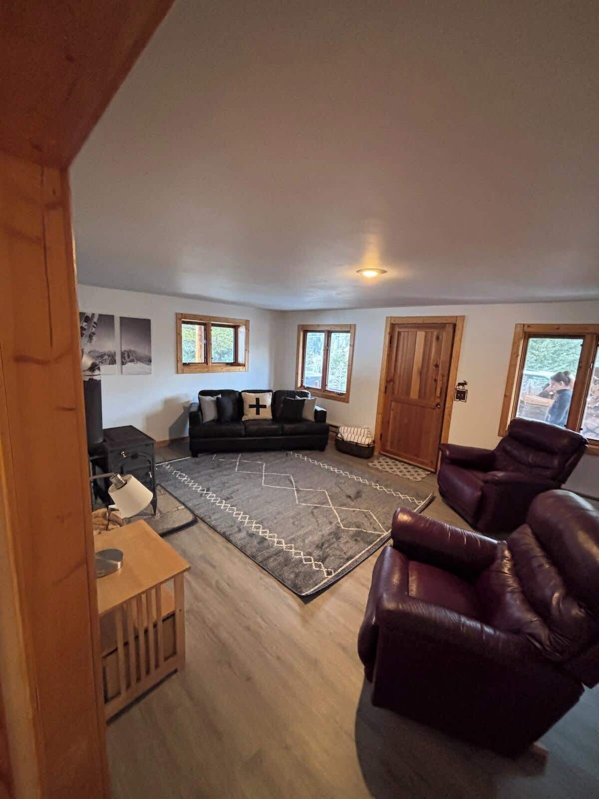 Un salon avec un canapé, deux fauteuils en cuir, un tapis et une cheminée.