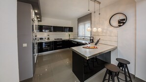 Una cocina moderna con una isla central, taburetes de bar e iluminación colgante.