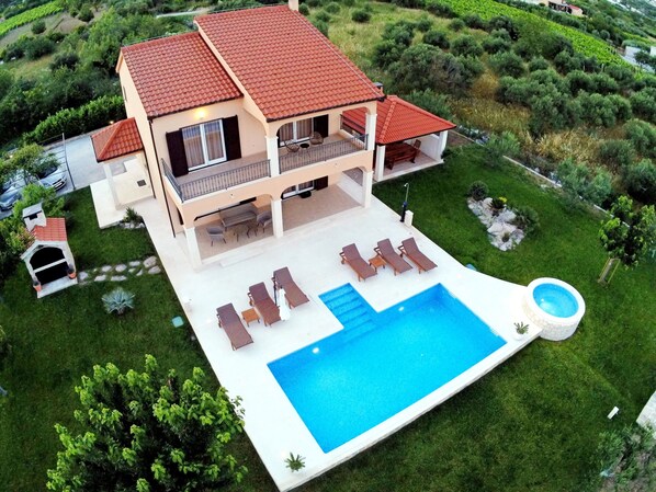 Ein zweistöckiges Haus mit Swimmingpool, Sitzgelegenheiten im Freien und einem Garten.