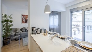 A modern kitchen with a dining area, a large window, and a balcony view. - Alterra Vita City Apartment (Thessaloniki)