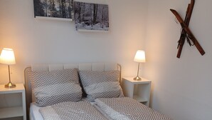Un letto rifatto con lenzuola fantasia, due comodini con lampade e due quadri appesi al muro.