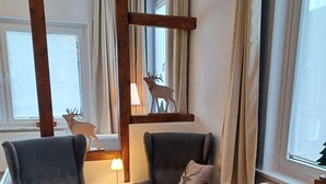 Un accogliente soggiorno con due poltrone, un poggiapiedi, una lampada e una decorazione a forma di cervo sul muro.