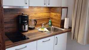 Una cucina con una macchina da caffè Bosch, una caraffa in vetro, una bottiglia verde e un lavello.