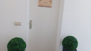Una porta con un cartello di benvenuto, un tappetino d'ingresso e due piante in vaso.