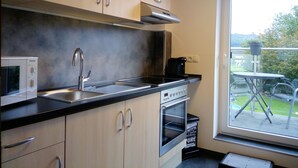 Une cuisine moderne équipée d’appareils électroménagers en acier inoxydable, d’un four encastré et d’une fenêtre donnant sur un jardin.