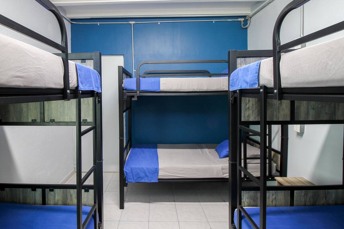 Een slaapkamer met stapelbedden, blauw-witte beddengoed, een blauwe wand en een betegelde vloer.