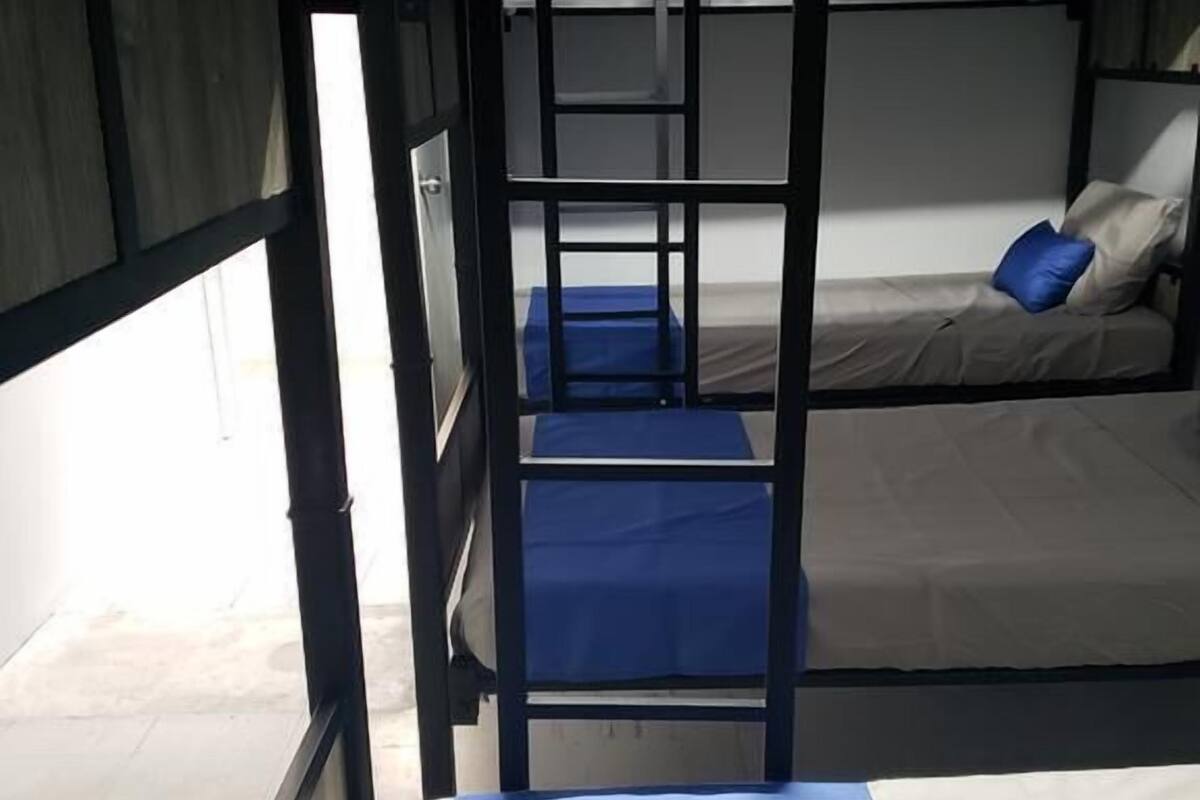 Een slaapkamer met een stapelbed, een blauwe matras en een raam aan de linkerkant.