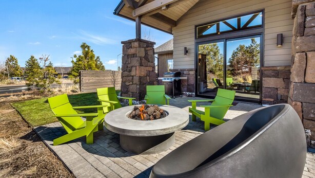 Un patio al aire libre con una chimenea, sillas verdes y una chimenea de piedra.