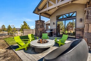 Un patio al aire libre con una chimenea, sillas verdes y una chimenea de piedra.