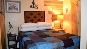 Une chambre à coucher avec un grand lit, une tête de lit en bois, une lampe fixée au mur et une porte avec un panneau en bois.