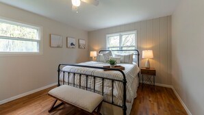 Ein Schlafzimmer mit einem Bett, Nachttischen, einer Bank und Kunstwerken an der Wand.
