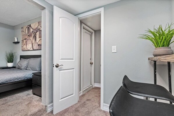 A bedroom with a bed, a chair, a door, and a plant. - Comfortable Guest Suite in Clearwater (GH2) (Safety Harbor)