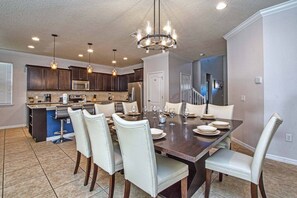A spacious kitchen with dark wooden cabinets, a central island, and a dining area with a large table and chairs.