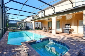 A swimming pool with a glass enclosure, a barbecue area, and outdoor seating.