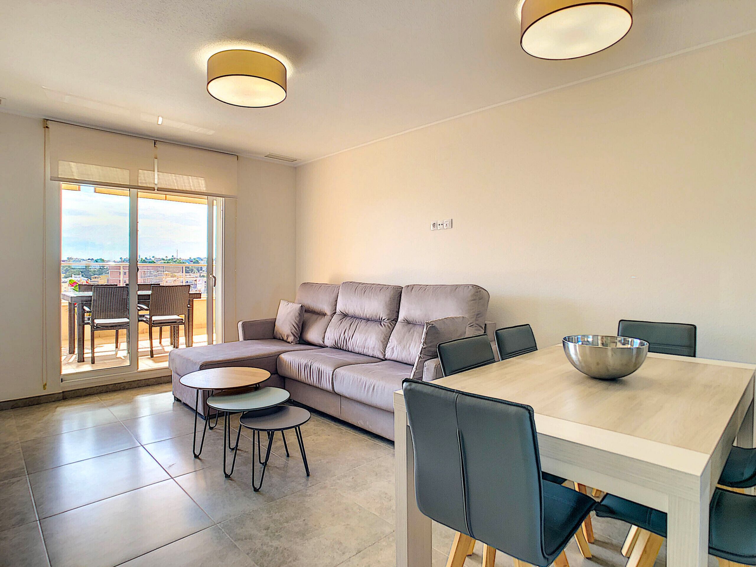 A modern living room with a sofa, dining table, chairs, and a large window.