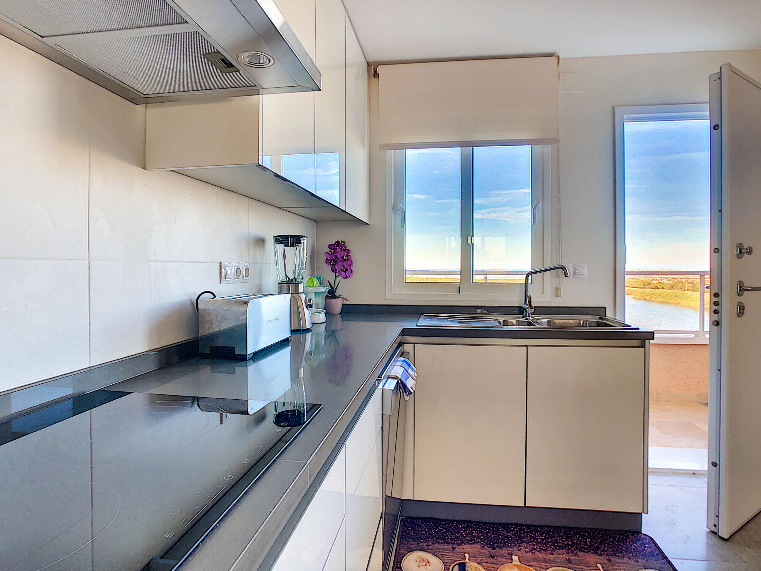 Una cocina moderna con una isla integrada, un tostador, una licuadora y un ventanal con vistas.