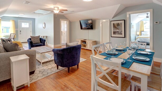 A spacious living area with a dining table set for four, a blue armchair, and a sofa. - Heated Pool Access, Large Tybee Home (Tybee Island)