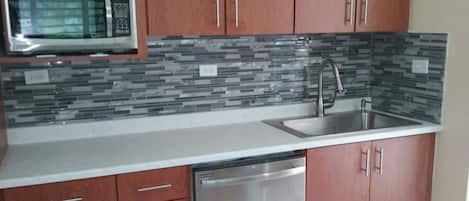A kitchen with wooden cabinets, a stainless steel sink, and a microwave.