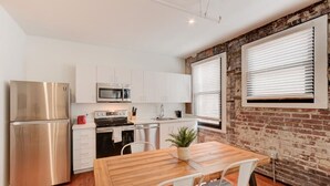 Une cuisine moderne dotée d’appareils électroménagers en acier inoxydable, de meubles blancs et d’un mur d’accent en briques.