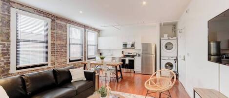 A modern apartment with a living room, dining area, kitchen, and laundry area.
