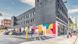 Un edifici modern amb façana de maó, grans finestres i un mural colorit a la planta baixa.