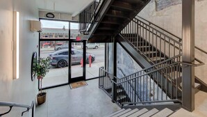 A modern interior with a staircase, a glass door leading outside, and a potted plant. - Prime Downtown Hub | Walk to Beale, Culture & Eats (Memphis)