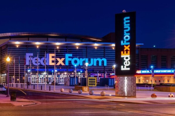 Une vue du bâtiment FedExForum, avec un grand panneau lumineux, un parking et une vue sur la rue.