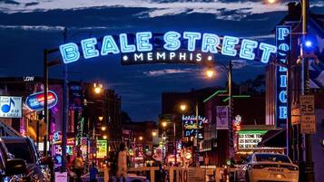 Een drukke straat met neonreclames, waaronder "Beale Street Memphis" en "Police".