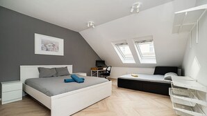 A modern loft bedroom with a large bed, a desk, and a loft bed with a desk.