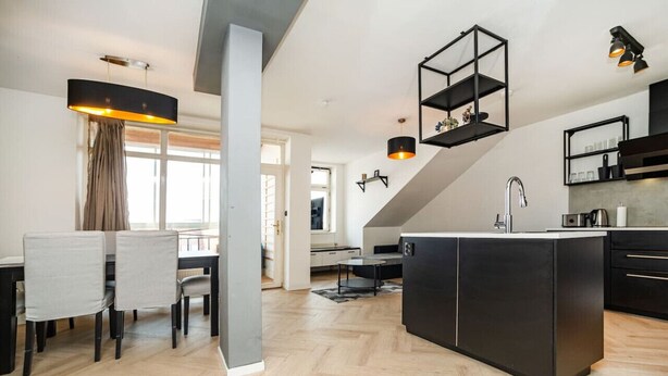 A modern kitchen with a central island, black cabinetry, and pendant lighting.