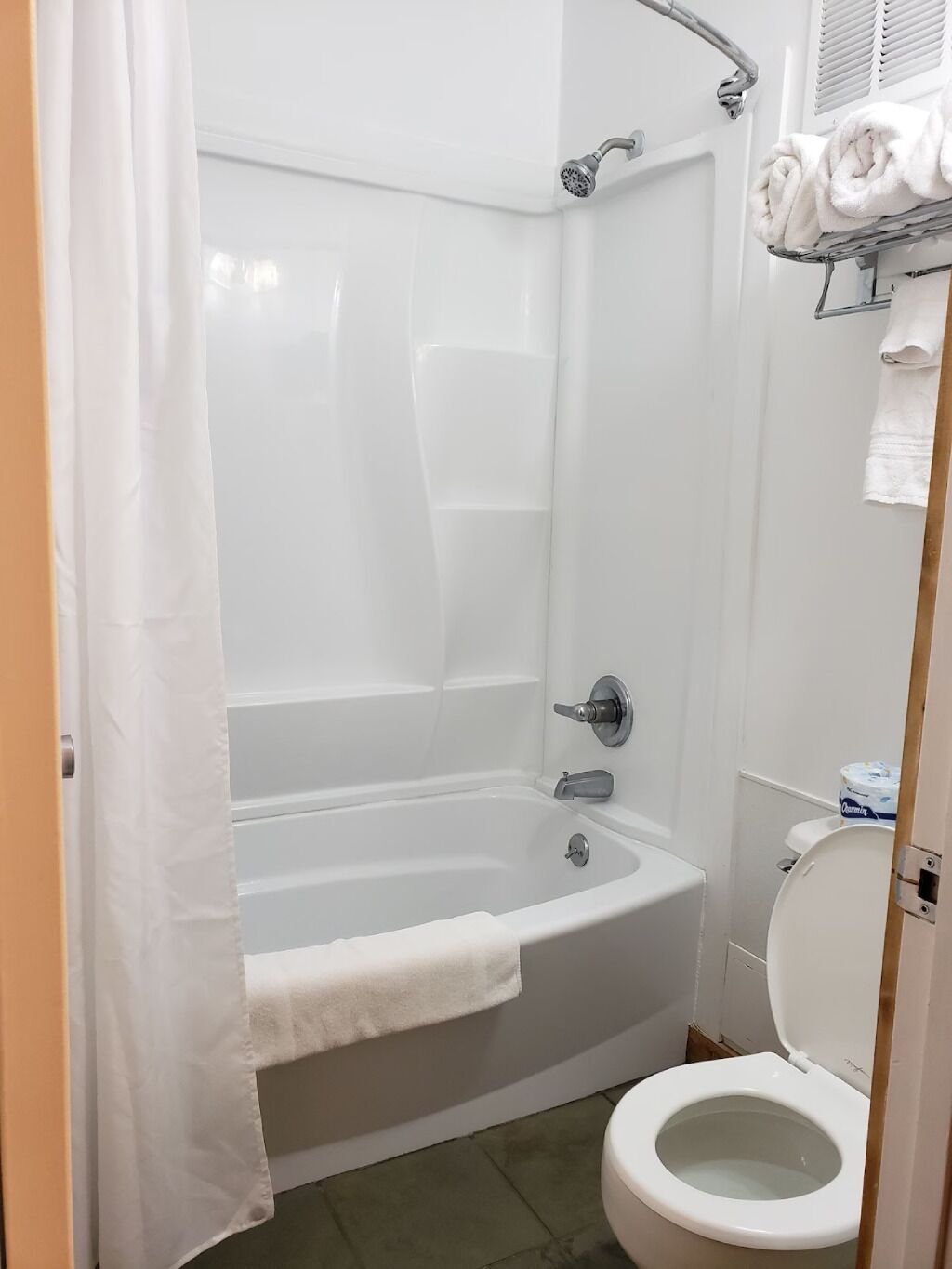 Et badeværelse med badekar, toilet og bruseforhæng.