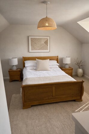 A bedroom with a wooden bed, two bedside tables, a hanging light fixture, a wall-mounted picture, and a floor-to-ceiling window.