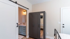 Une chambre à coucher comprenant un lit, une armoire et une salle de bain avec un lavabo et un miroir.