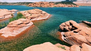 On peut clairement apercevoir une côte rocheuse bordée d’une eau calme, le tout étant entouré de collines.