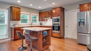 A modern kitchen with wooden cabinets, stainless steel appliances, and a central island with bar stools. - Cardinal's Nest - Secluded 9+ Acres, 3,000+ sq. ft., firepit in Columbia, TN (Columbia)