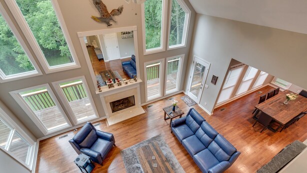 A spacious living area with a fireplace, large windows, and a dining area. - Cardinal's Nest - Secluded 9+ Acres, 3,000+ sq. ft., firepit in Columbia, TN (Columbia)