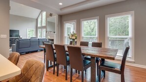 A spacious living area with a dining table, chairs, and a sofa. There are large windows with blinds, a fireplace, and a television in the background. - Cardinal's Nest - Secluded 9+ Acres, 3,000+ sq. ft., firepit in Columbia, TN (Columbia)