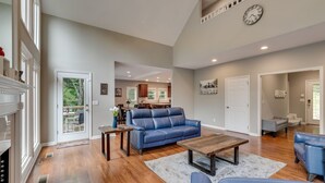 A spacious living room with a blue leather sofa, wooden coffee table, and a fireplace. - Cardinal's Nest - Secluded 9+ Acres, 3,000+ sq. ft., firepit in Columbia, TN (Columbia)